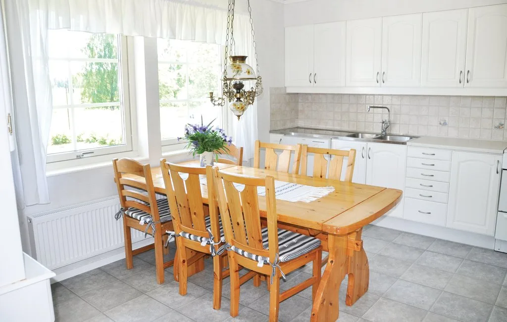 A bright kitchen dining area with a wooden table and white cabinets.