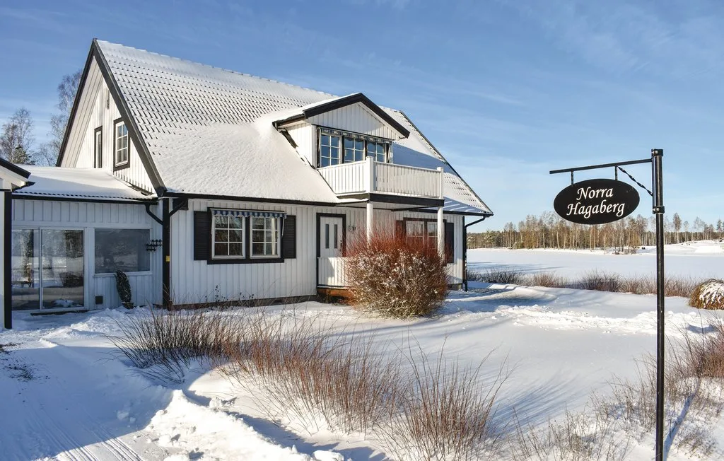 A white house stands beside a snowy yard beneath a clear winter sky.