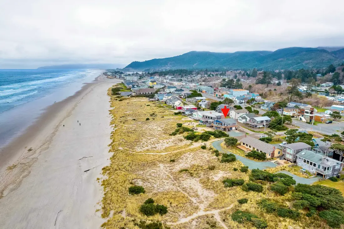 Aerial view of a coastal town beside a broad sandy beach and ocean.