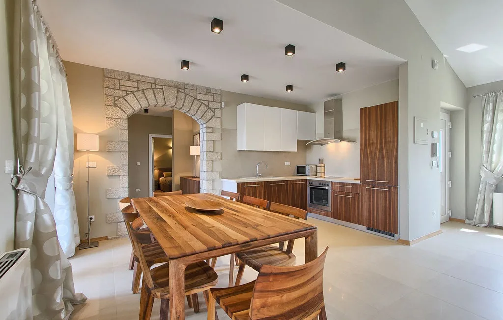 Un comedor con una mesa larga de madera junto a una cocina abierta.