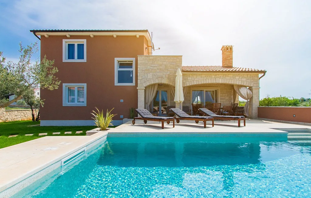 Una piscina frente a una casa con un patio cubierto.