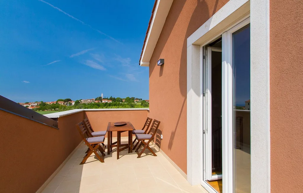 Una terraza soleada con asientos al aire libre y una puerta abierta.