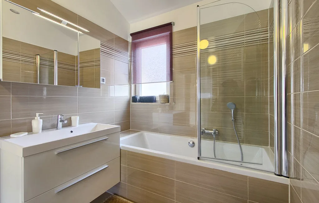 Un baño con lavabo, bañera y mampara de ducha de vidrio.