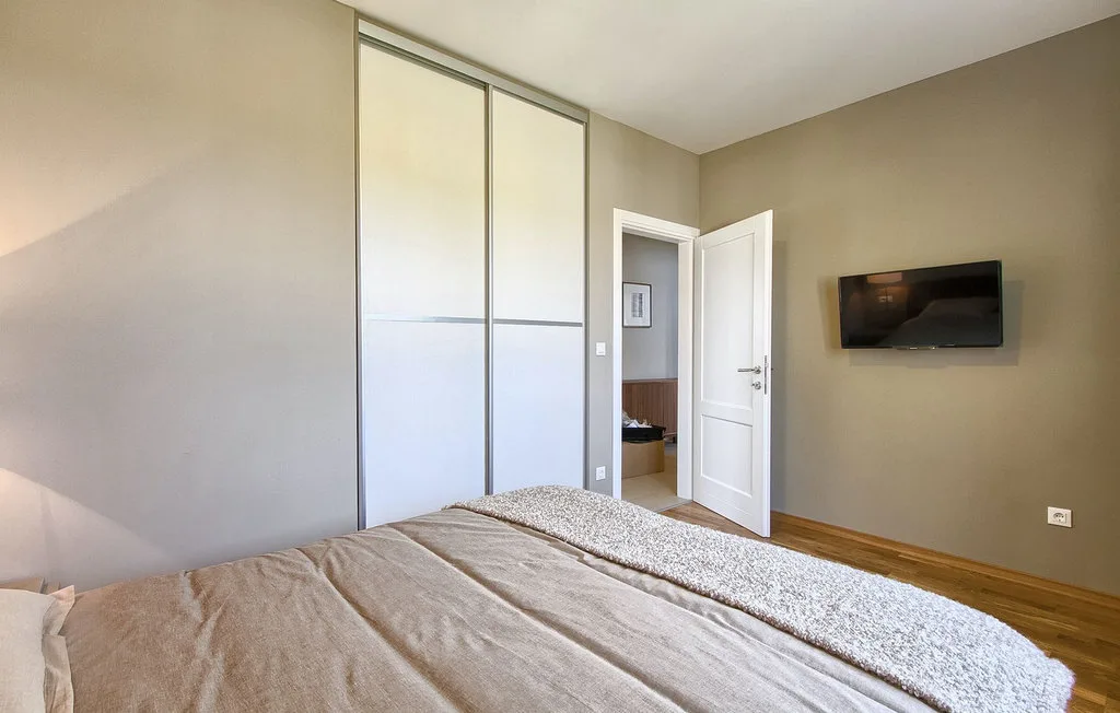 Un dormitorio con una cama, puertas corredizas de armario y un televisor en la pared.
