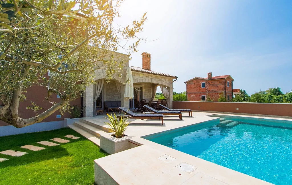 Una piscina junto a un patio pavimentado con asientos al aire libre.