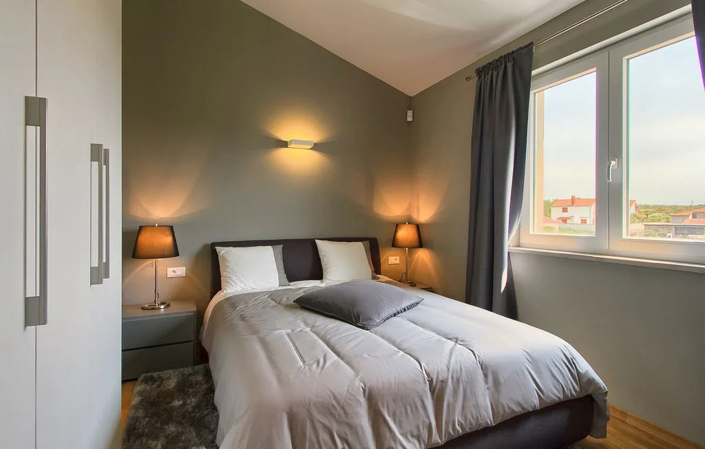 Un dormitorio con una cama bien tendida y una ventana grande.