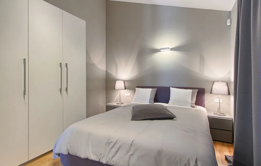 Un dormitorio con una cama bien tendida, mesitas de noche y un armario.
