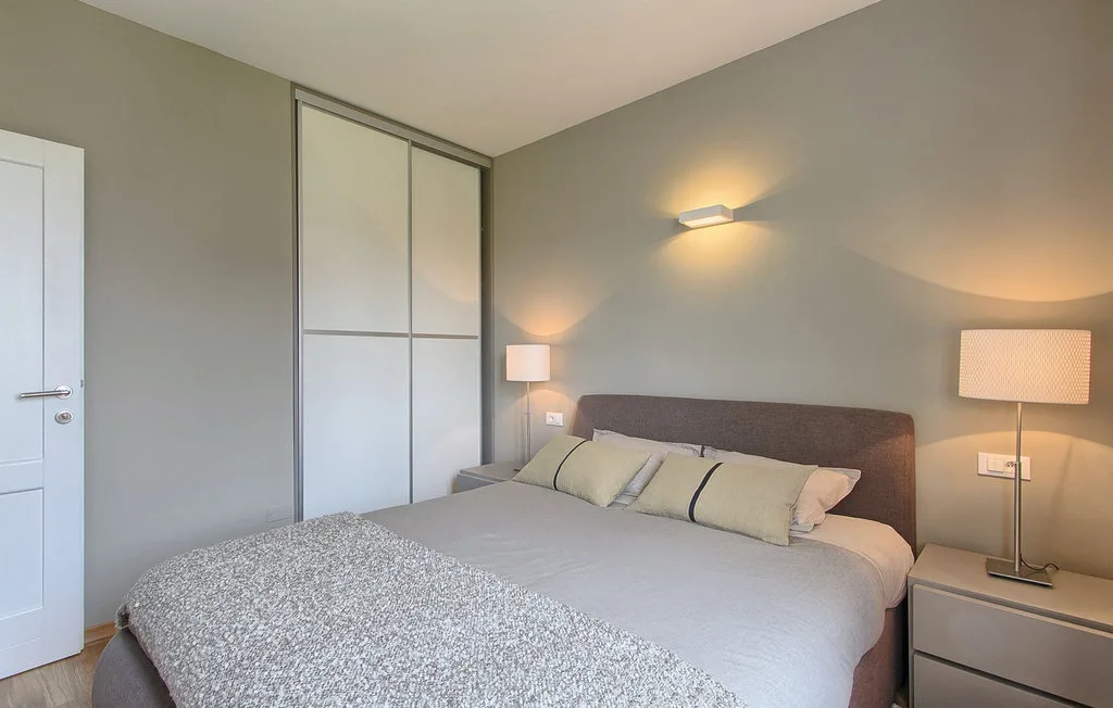 Un dormitorio con una cama tendida, mesitas de noche e iluminación cálida.