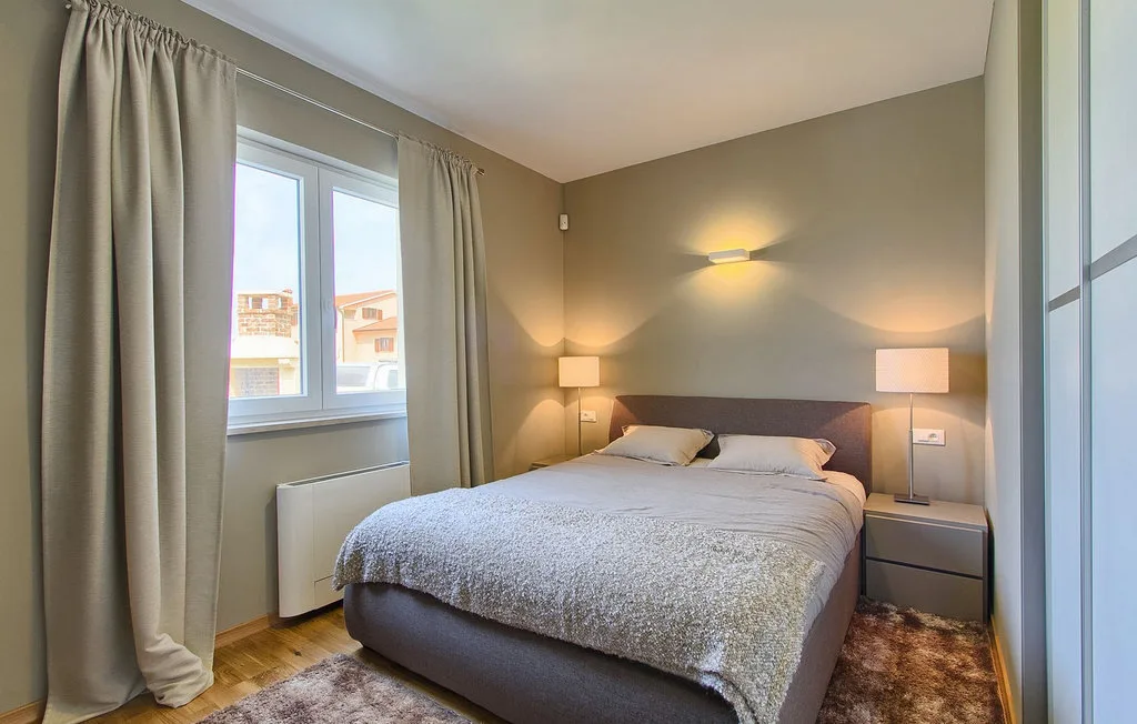 Dormitorio con una cama, mesas de noche y una ventana con cortinas.