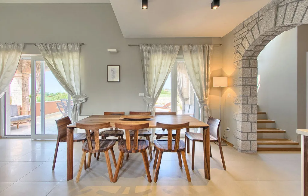 Comedor con una mesa de madera y sillas junto a ventanas luminosas.