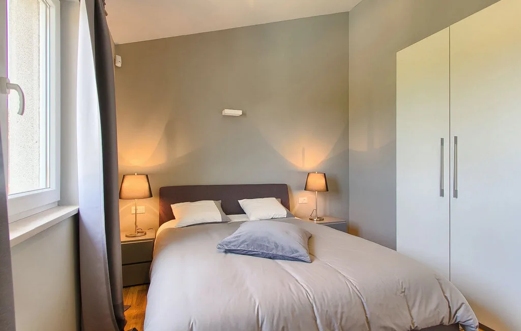 Un dormitorio con una cama doble, mesitas de noche y un armario.