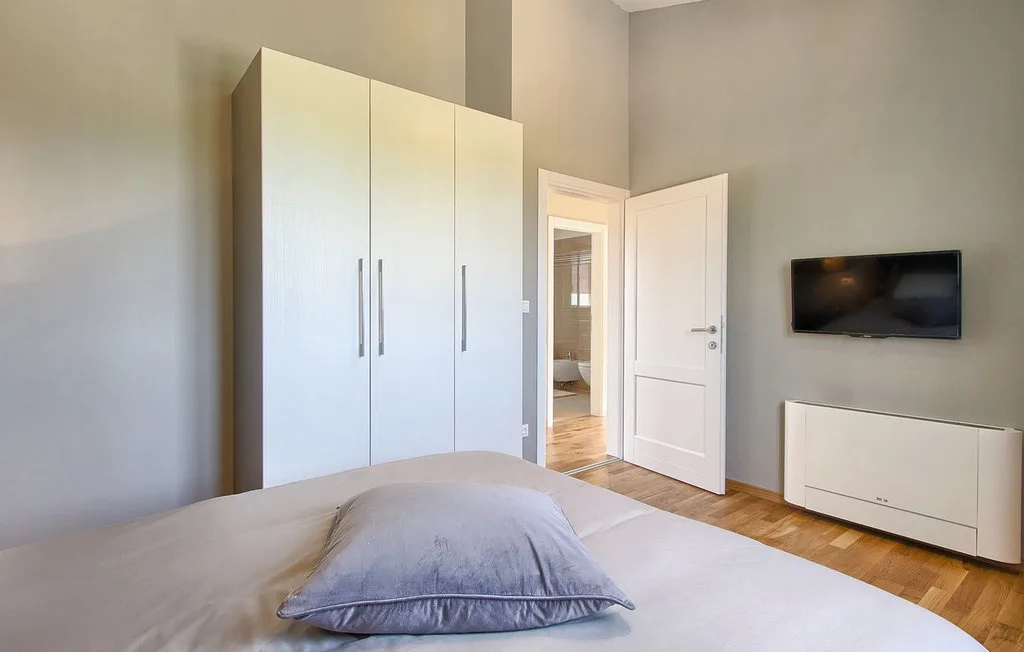 Un dormitorio con una cama, un armario y un televisor en la pared.