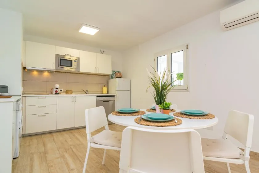 A bright dining area with a round table beside a compact kitchen.
