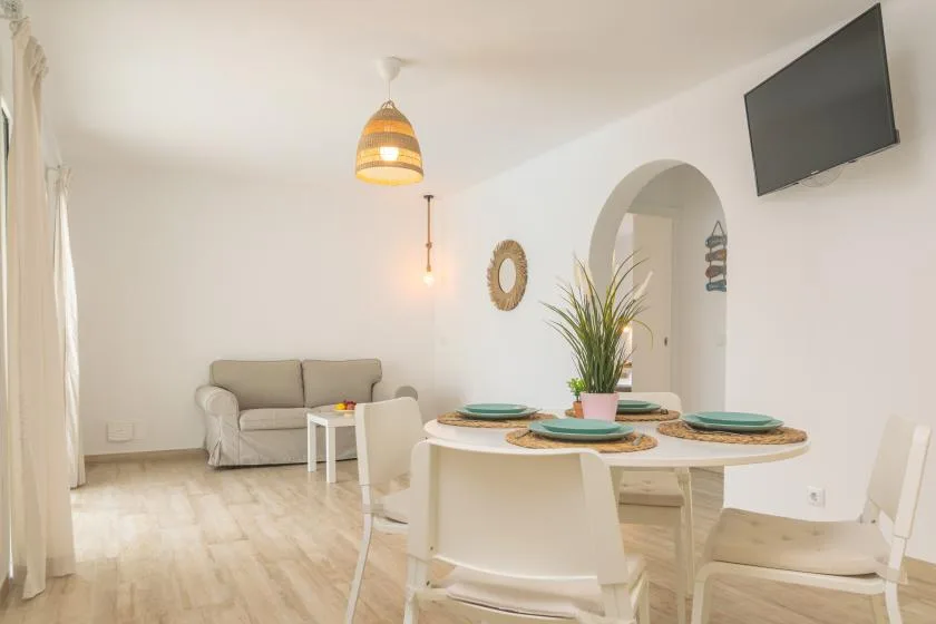 A bright dining area with a set table and a small seating area in the background.