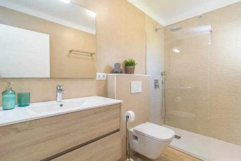 A bathroom with a long sink counter and a glass shower area.
