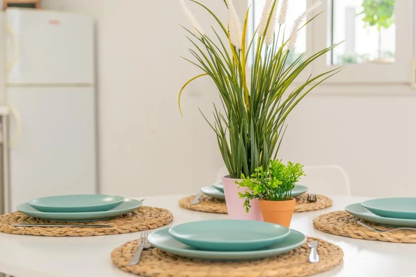 A bright dining area with place settings and potted plants on a table.