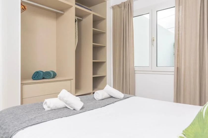 A bedroom with a bed, built-in shelving, and a curtained window.