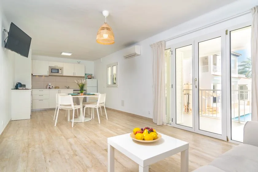 Una luminosa sala de estar diáfana con mesa de comedor y puertas de vidrio que dan a un balcón.