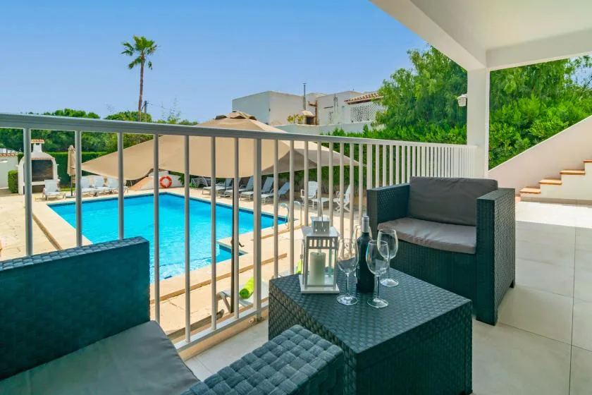 Una zona de estar en una terraza cubierta da a una piscina y tumbonas a la sombra.
