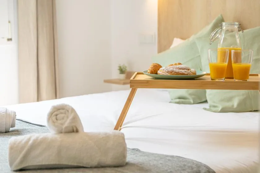 A bright bedroom with a breakfast tray resting on the bed.