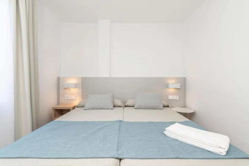 A bright bedroom with a neatly made bed and folded towels.