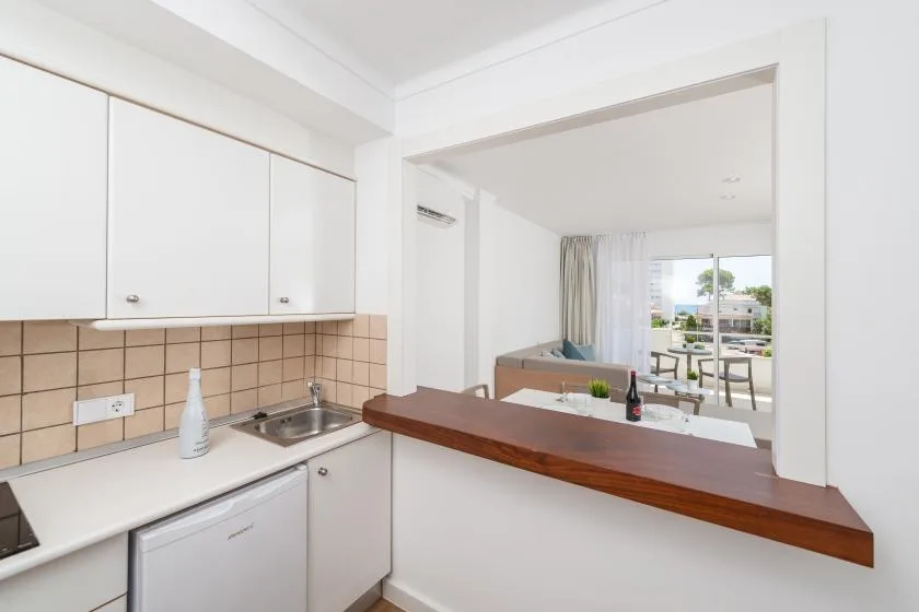 A bright kitchen opens onto a living area with a window and balcony.