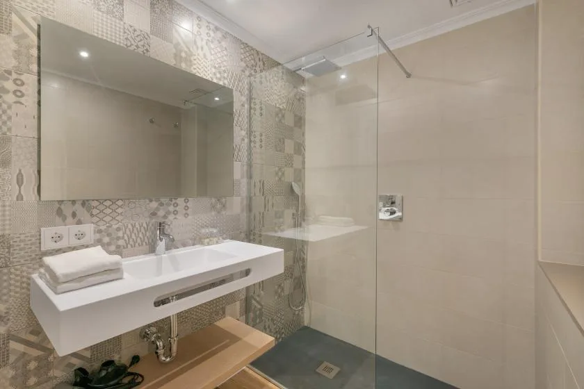 A modern bathroom with a wall-mounted sink and a glass shower screen.