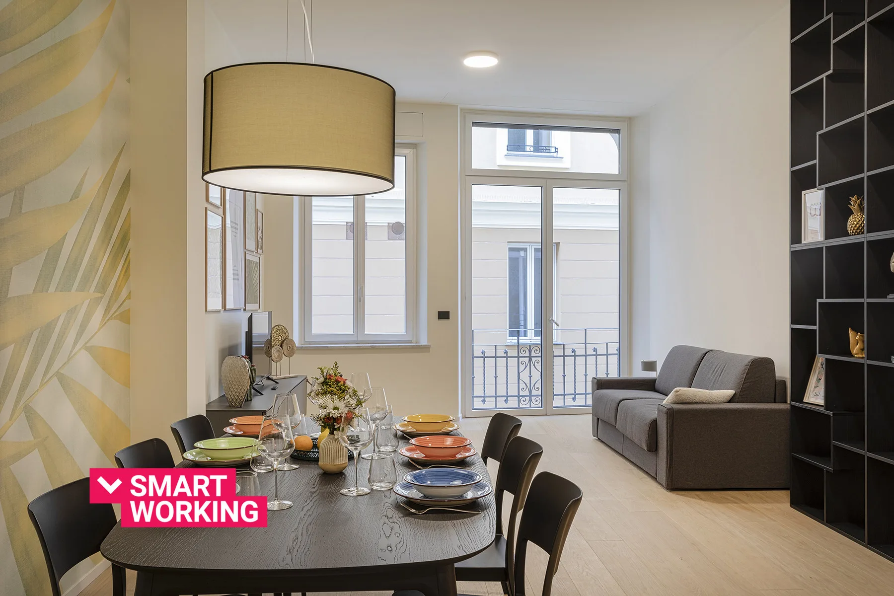 A dining area with a set table beside a living space and large windows.