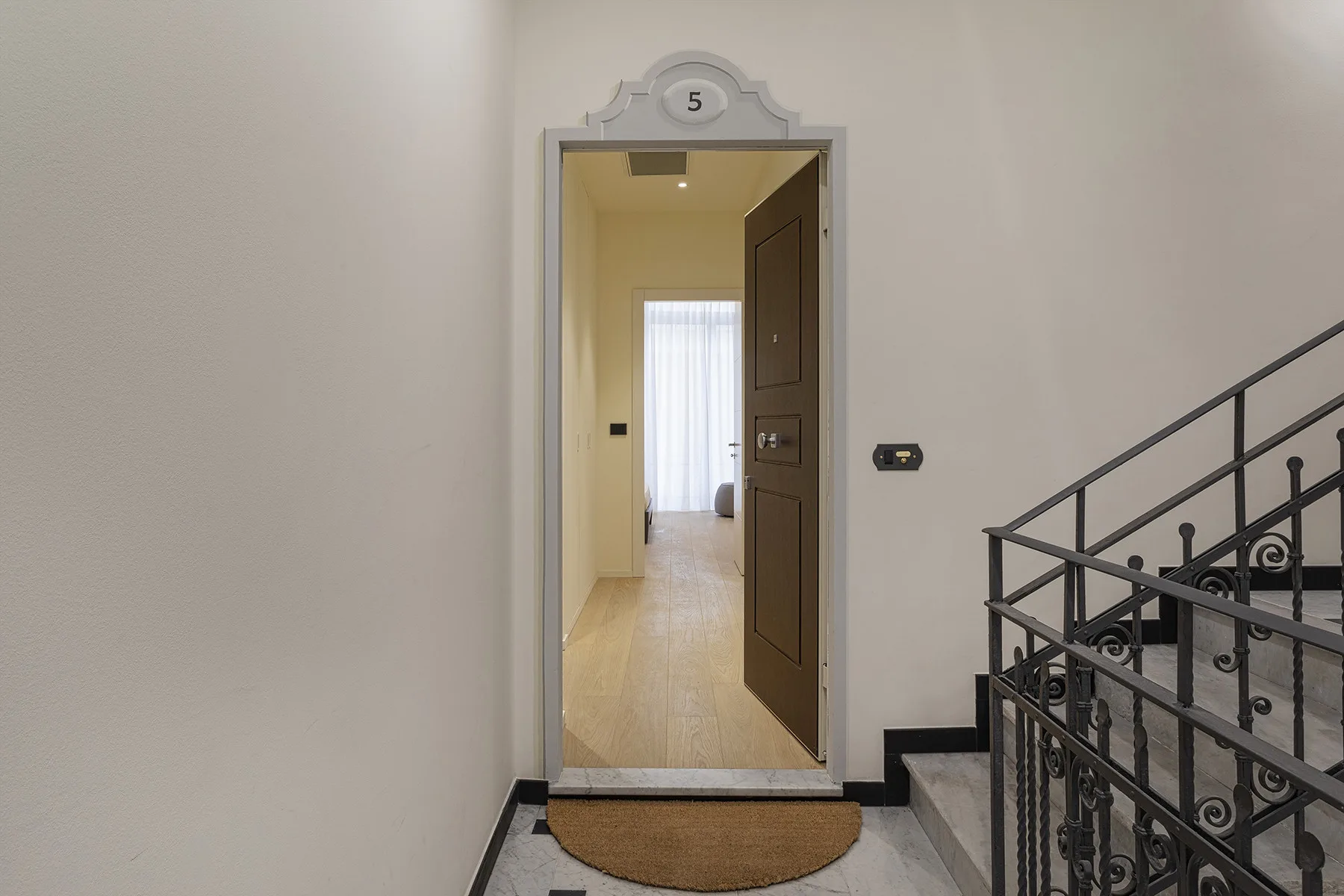 A hallway entrance opens onto a bright corridor with a window at the far end.