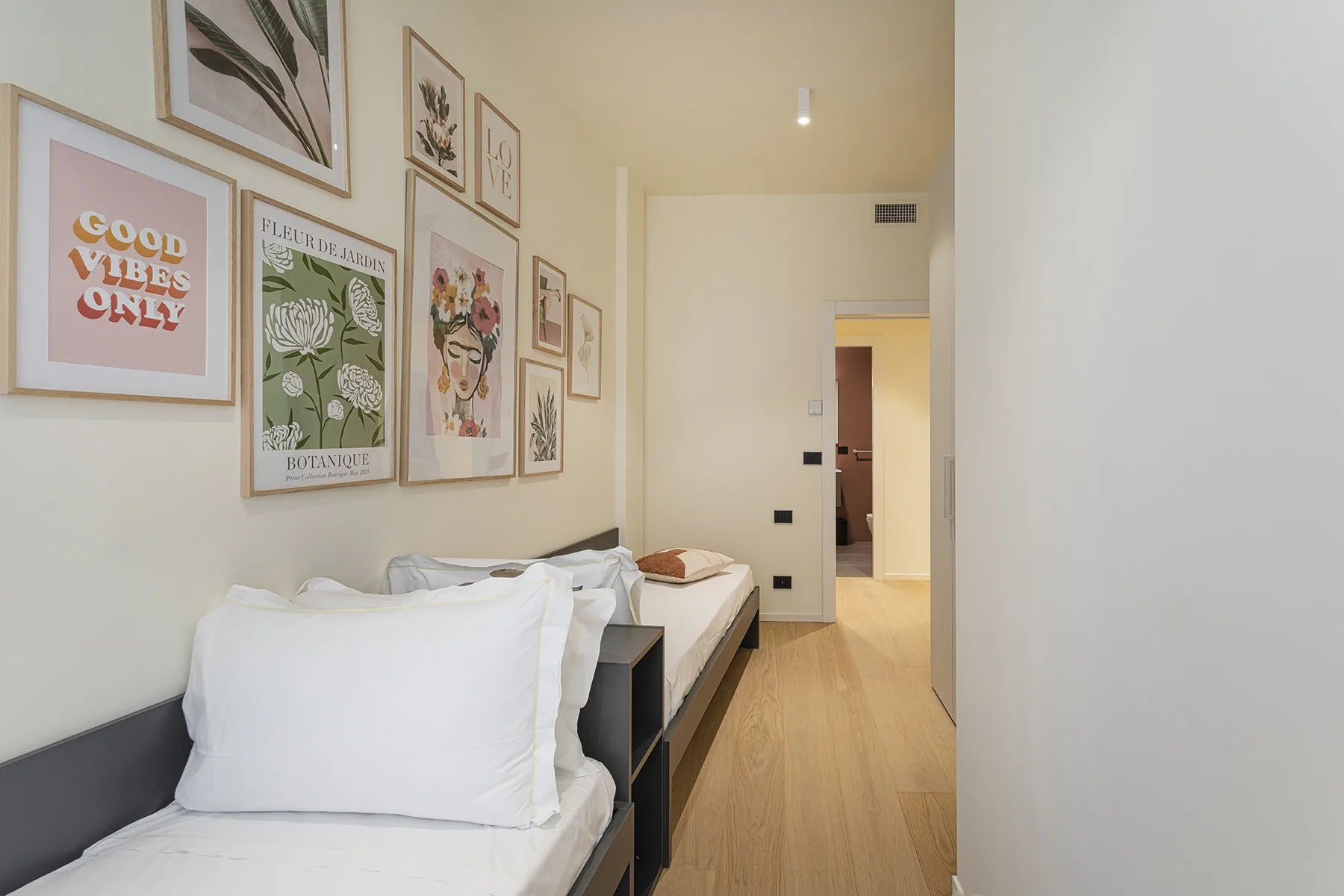 A bedroom with two single beds and framed artwork on the wall.