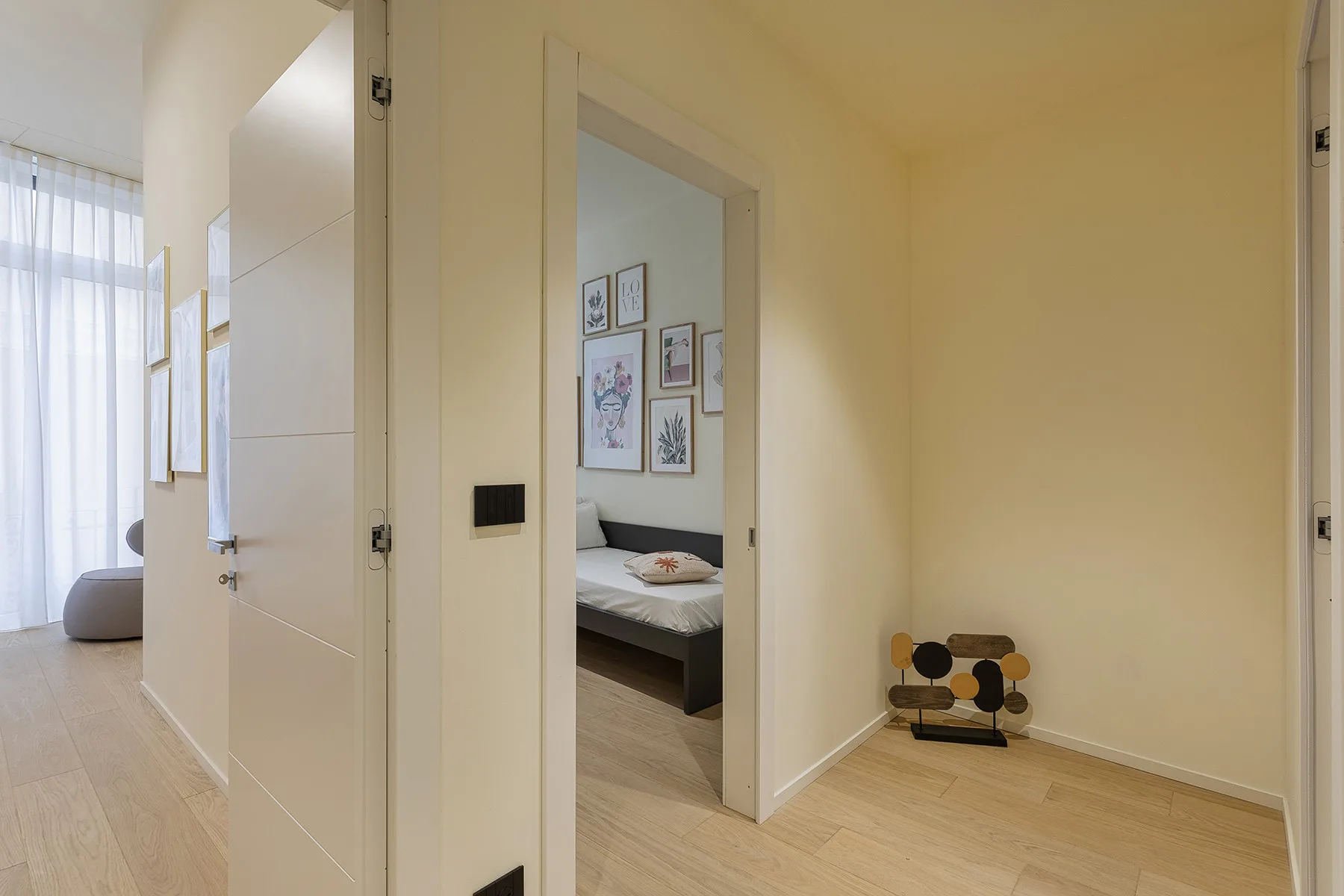 A hallway opens into a bedroom with framed artwork above the bed.