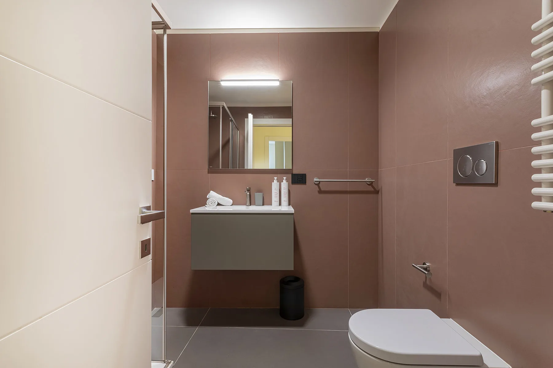 A modern bathroom with a sink, mirror, and toilet.