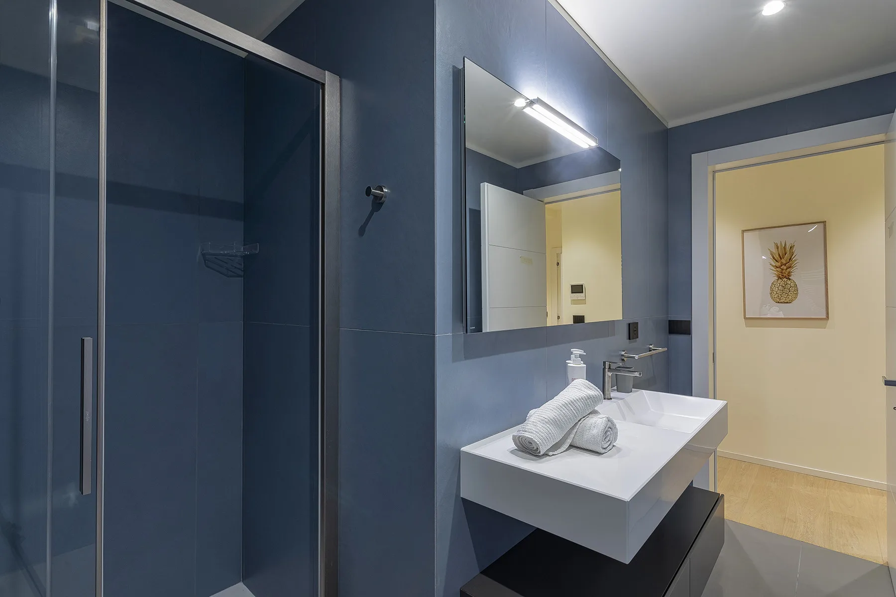 A modern bathroom with a glass shower, a white sink, and a wall mirror.