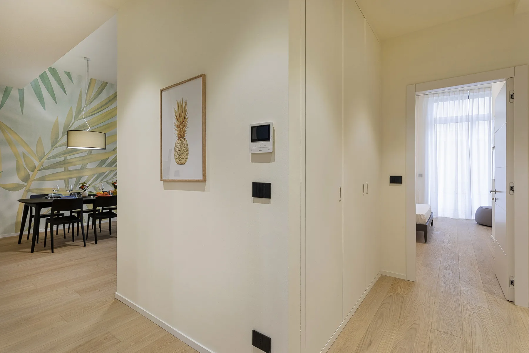 A bright interior hallway opens onto a dining area and a room with a curtained window.