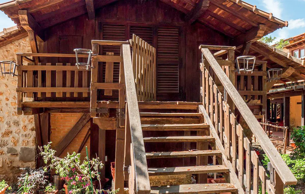 An outdoor wooden staircase leads to a raised entrance beside a stone wall.