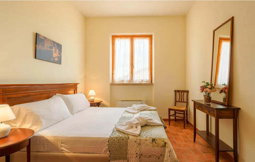 A bedroom with a bed, a window, and a small table.