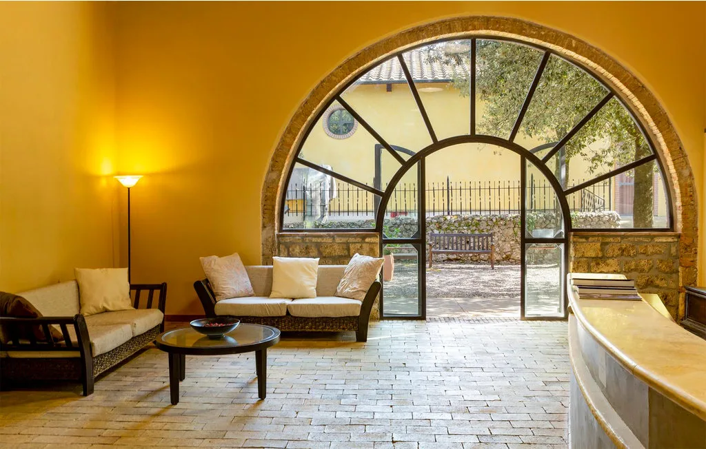 A bright lounge with seating around a large arched window.