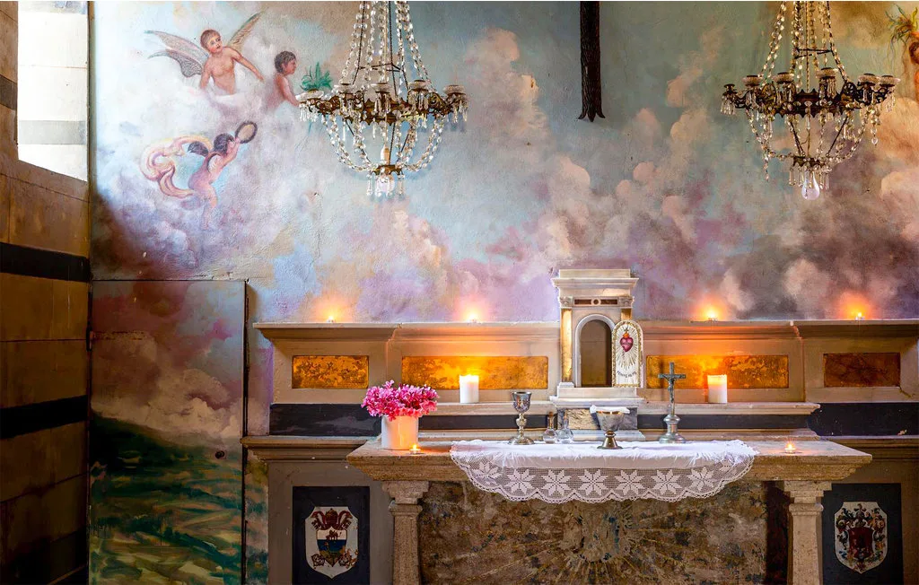 An ornate chapel altar stands beneath chandeliers and a painted ceiling.
