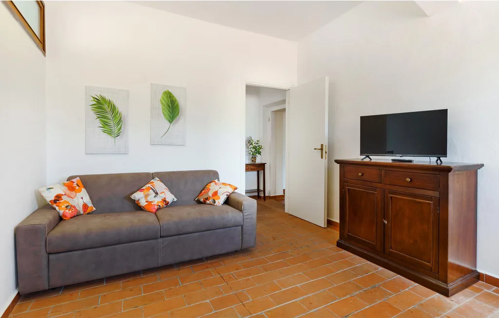 A living room with a gray sofa and television on a wooden cabinet.