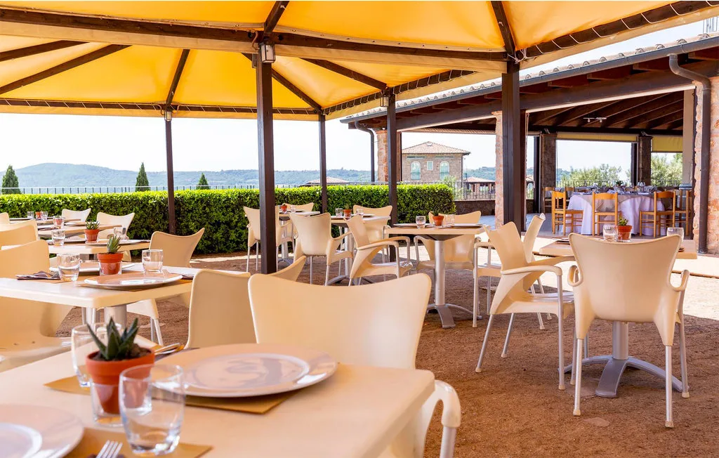 An outdoor dining area beneath a yellow canopy, with tables and seating.