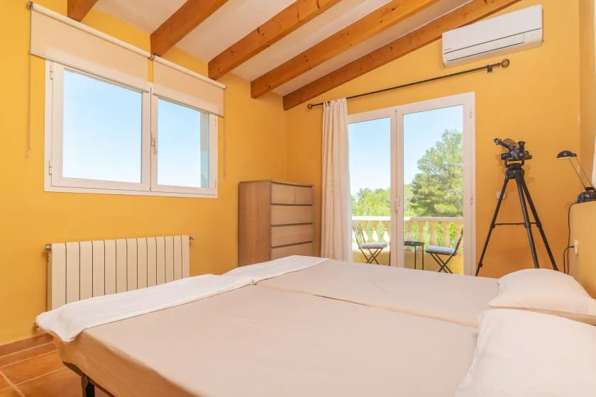 A bedroom with a bed, windows, and glass doors opening onto a balcony.
