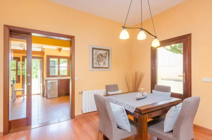 A dining area with a wooden table, upholstered seating, and pendant lights.