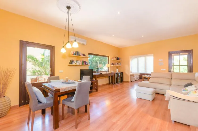 A bright living and dining area with a dining table, seating, and bookshelves.