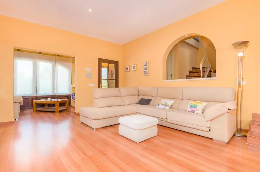 A living room with a sectional seating area and a large arched opening.