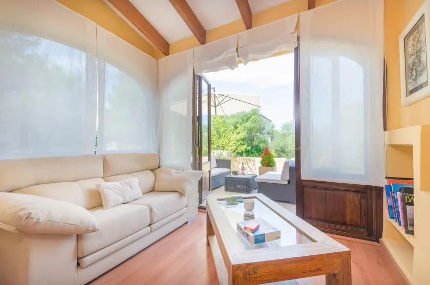 A bright living room with a sofa and coffee table beside an open doorway.