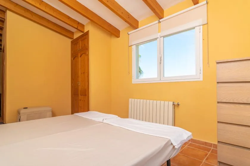 A bedroom with a bed, a window, and a wooden door.