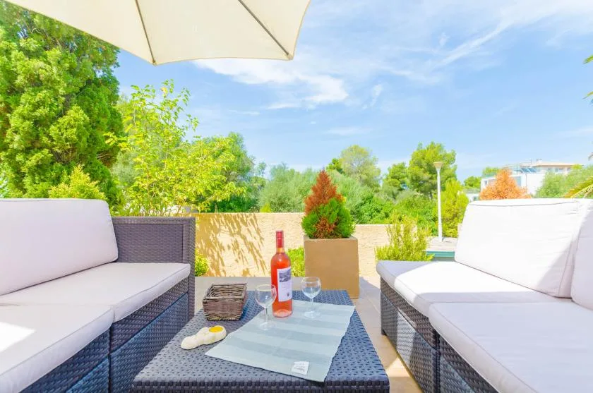 Outdoor patio seating surrounds a low table beneath a large umbrella.