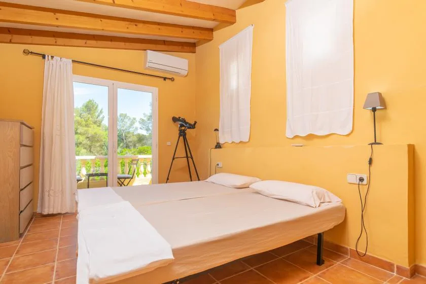 A bedroom with a large bed beside a glass door opening onto a balcony.