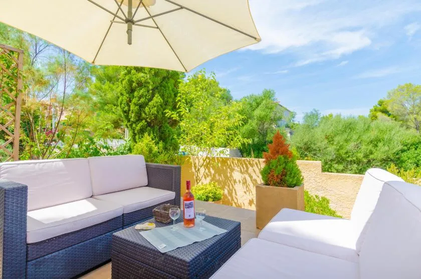 An outdoor patio seating area with a large umbrella and surrounding greenery.