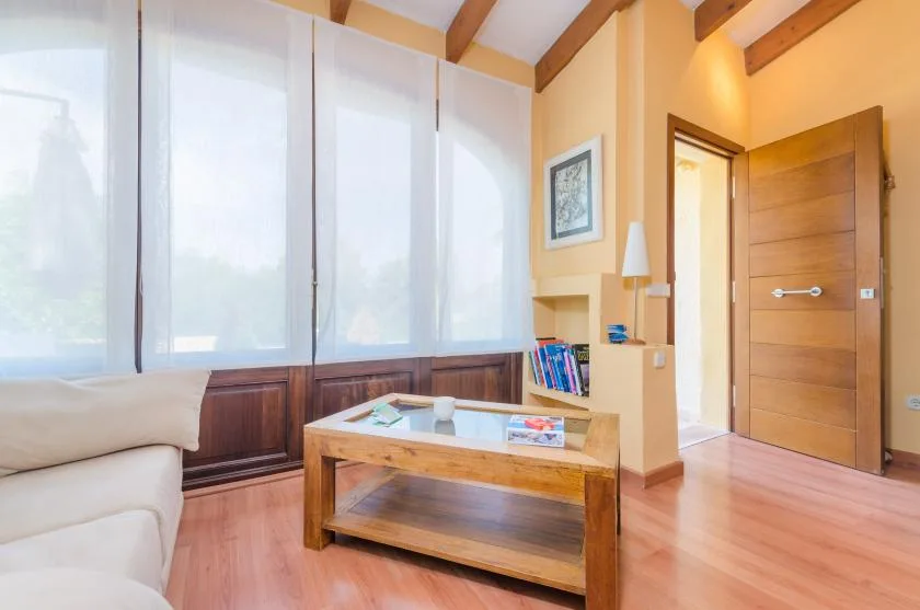 Una sala luminosa con una mesa de centro de madera y grandes ventanas.